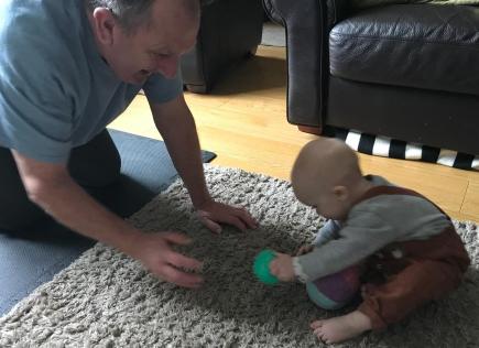 Playing roll the ball - baby and grandad